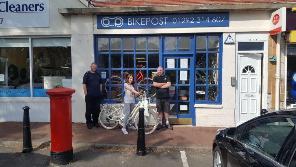 The Bike Post staff posing outside their storefront in Troon with the VOLT Kensington e-bike