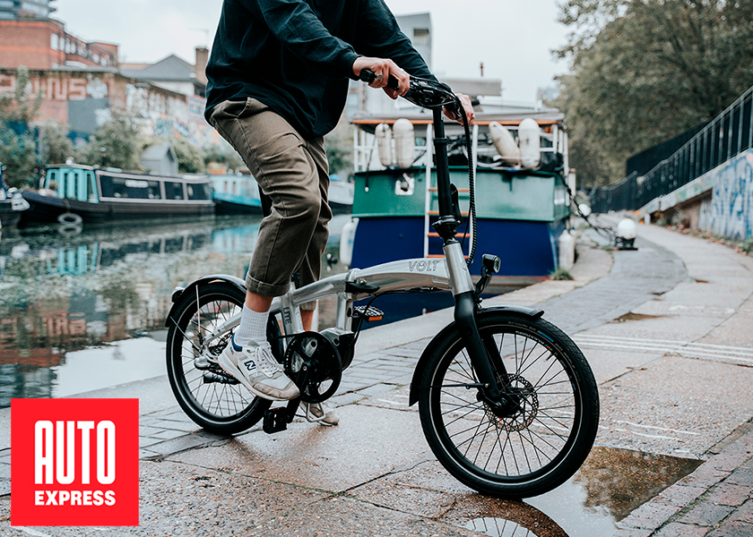 Urban commuter on a VOLT Lite electric folding bike near canal boats, showcasing eco-friendly city transport