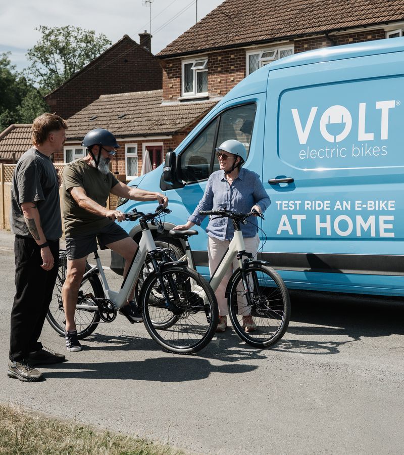 Two riders trying VOLT e-bikes beside the VOLT home test ride van